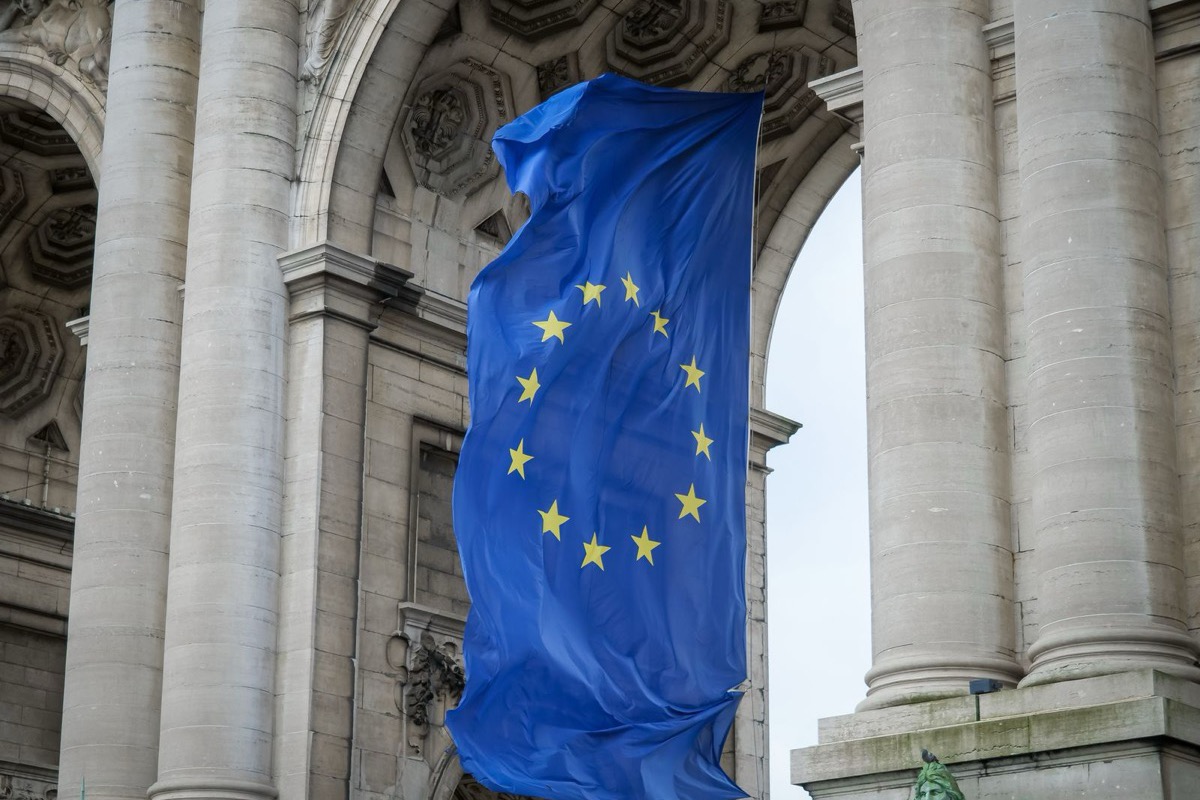 Cờ Liên minh châu Âu nền xanh với vòng mười hai ngôi sao vàng tung bay dưới vòm Khải Hoàn Môn Cinquantenaire ở Brussels, Bỉ