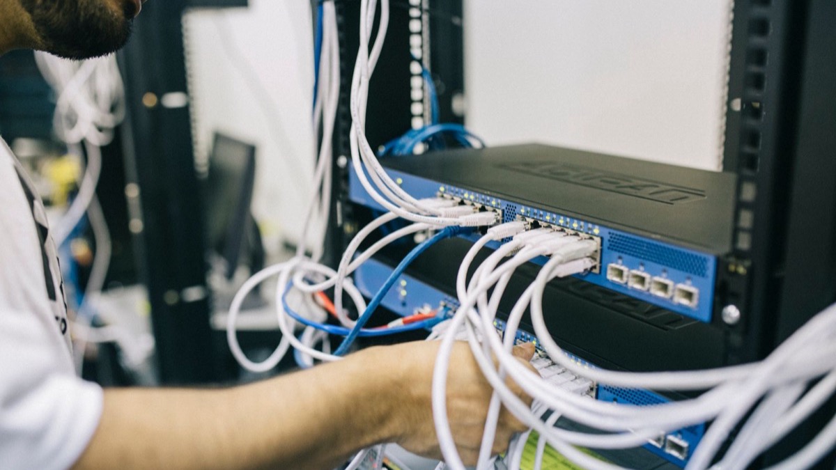 Kỹ thuật viên cắm dây mạng vào switch trong rack máy chủ, minh họa hạ tầng tự host mô hình mở on-premise