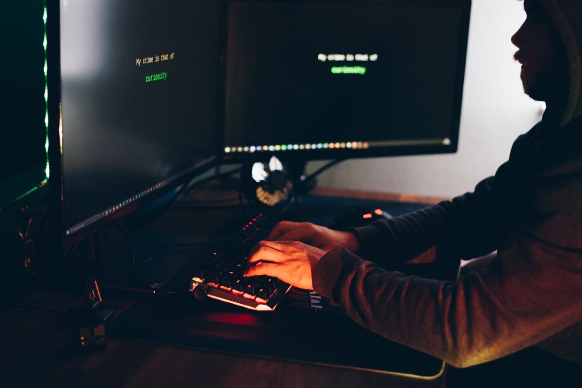 Hacker trùm mũ gõ bàn phím trong bóng tối