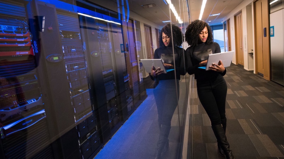 A professional using a laptop beside server racks, illustrating the human factor behind shadow-AI risk in the enterprise